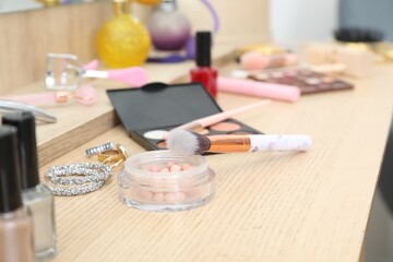 Makeup room. Different beauty products and jewelry on wooden dressing table, closeup