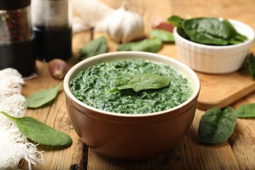 Delicious spinach sauce in bowl and leaves on wooden table, closeup