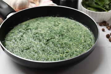Delicious spinach sauce served on white tiled table, closeup