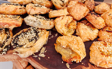 Small boreks оr bourekas with sesame seeds on wooden tray