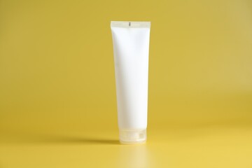 Tube of cosmetic product on yellow background