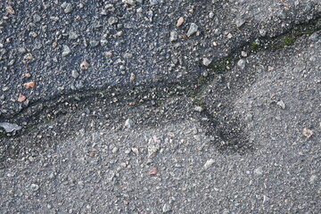cracks in the asphalt after frost, cracked texture of grey bitumen, road surface covered with snow after winter 