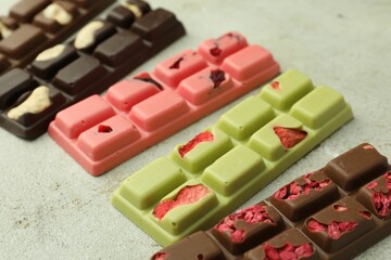 Delicious chocolate bars with different flavors on light table, closeup