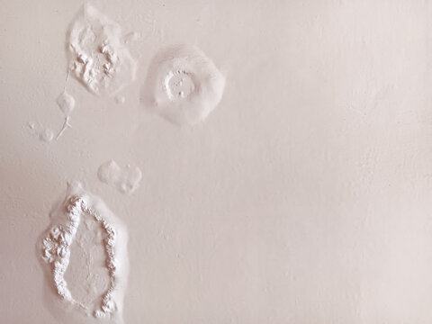 Abstract texture of paint blisters or bubbles on a white wall.