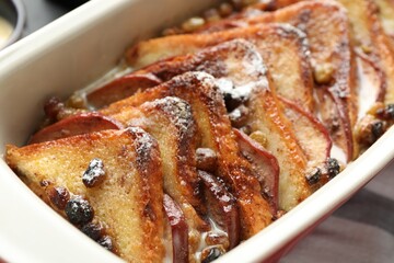 Freshly baked bread pudding in baking dish on table, closeup