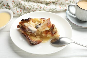 Freshly baked bread pudding and spoon on white wooden table, closeup