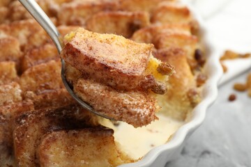Eating delicious bread pudding with cinnamon at table, closeup