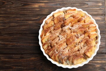 Delicious bread pudding with raisins and cinnamon on wooden table, top view. Space for text