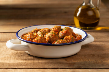 Delicious homemade vegan meatballs, served in a casserole dish on a rustic wooden table...