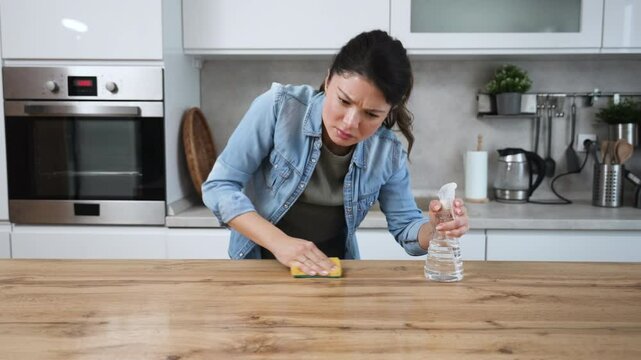 Young landlady making a big cleaning for the apartment she is renting out, to be clean for the new tenants to whom she rented out the apartment. Homeowner or woman rubbing the kitchen working top.