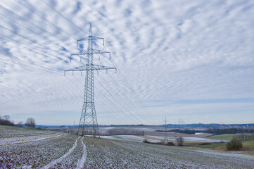 Strommast / Hochspannungsleitung / Hochspannungsmast (Überlandleitung) in eisiger Winterlandschaft mit dramatischem Himmel - Elektrizität