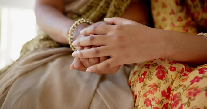 Holding hands, two indian mother and daughter in traditional Indian sari showing support and care