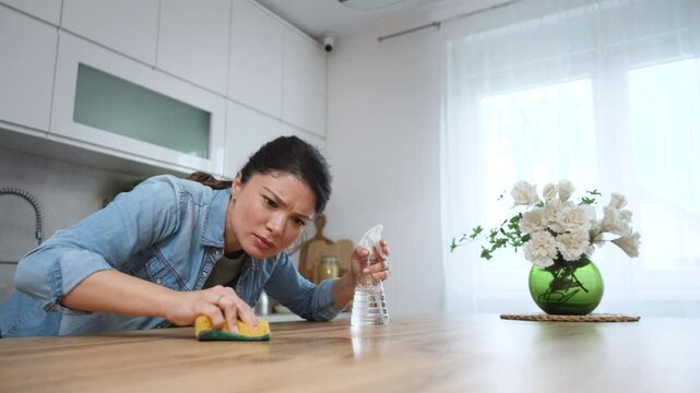 Young landlady making a big cleaning for the apartment she is renting out, to be clean for the new tenants to whom she rented out the apartment. Homeowner or woman rubbing the kitchen working top.
