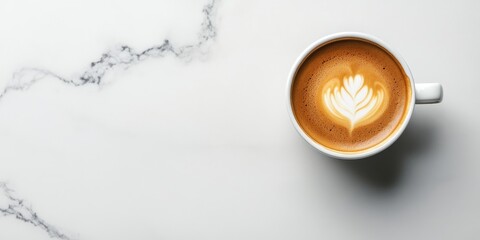 Birdseye view of a latte art on brown coffee in a white cup positioned center on a light grey and white marble surface
