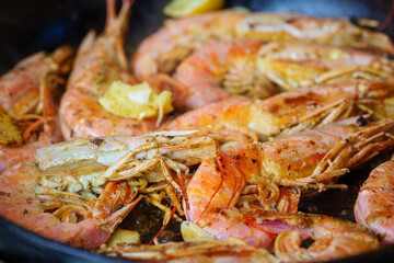 Langoustines with Lemon Pepper Butter. Fried shrimps. Grilled large shrimps, longoustine cooked in a frying pan with spices, herbs and lemon on a dark background. 