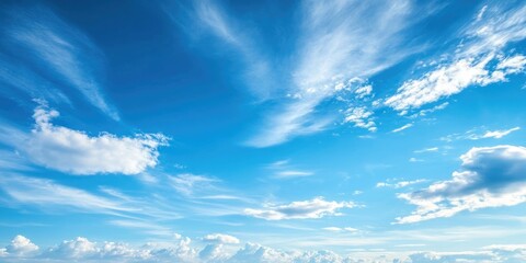 Vibrant blue sky with wispy white clouds scattered across the horizon creating ample copy space for text overlay in a serene natural setting