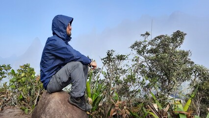 homem em mirante com dedo de deus ao fundo, na serra dos órgaõs, rio de janeiro 