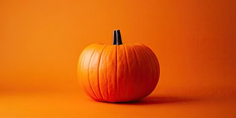 Vibrant orange pumpkin centered on an orange background showcasing rich textures and smooth curves...