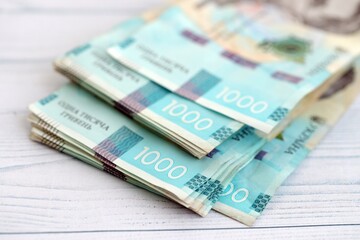 Big amount of ukrainian new one hundred hryvnia money bills with modern design on white wooden table. Financial concept, business