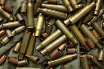 Many used rifle cartridges on military camo green fabric background