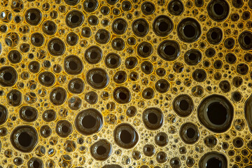 Close up of a cup of black coffee. Milk in coffee close-up top view. Black coffee with milk cream foam texture. Coffee foam macro.
