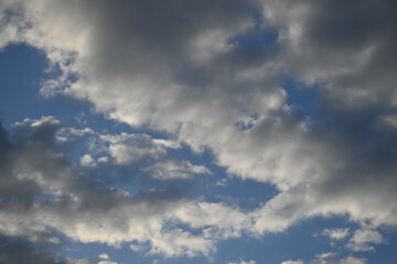 rays of the sun through cirrus clouds against a blue sky, white rainy clouds against a blue sky illuminated by the rays of the sun	
