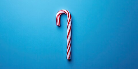 Candy cane positioned centrally on classic blue backdrop creating a minimalist aesthetic ideal for Christmas themed sweet food ideas