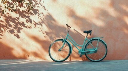 Fototapeta premium A beautifully styled turquoise bicycle with retro details, leaning against a pale coral wall under warm sunlight