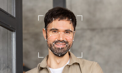 A smiling man stands in a contemporary space with facial recognition markers overlaying his face. This showcases the advancements in identification technology for security purposes.