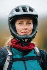 A woman wearing a helmet and a red scarf. She is smiling and looking at the camera. Concept of adventure and excitement, as the woman is likely preparing for a bike ride or other outdoor activity