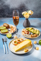 Gourmet dinner table setting featuring cheese, shrimp, and sparkling wine