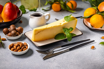 Gourmet cheese wedge with mint, fruits, and nuts on a table setting