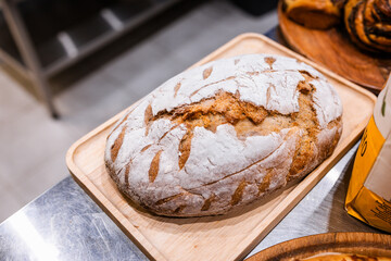 freshly baked wheat oval bread on a wooden board in the bakery kitchen, fresh pastries