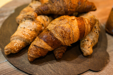 freshly baked wheat croissants on a wooden board in the bakery kitchen, fresh pastries