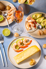 Gourmet dinner with shrimps, cheese, avocado, kiwi, and rose wine