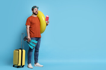 Traveller with passport, ticket, suitcase and beach accessories on light blue background, space for...