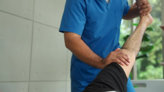 Young physiotherapist man stretching patients leg injury to recover rehabilitation physiotherapy at hospital, young man having leg treatment for wellness medical support concept.