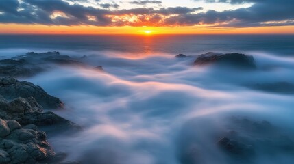 Naklejka premium Serene seascape at sunset with dramatic clouds and soft waves creating a tranquil atmosphere over rocky shoreline