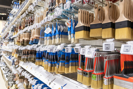 wide selection of paintbrushes on display in a hardware store aisle with colorful handles and price tags