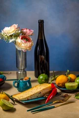 Fotobehang Eetkamer Gourmet cheese with chili pepper, fruits, and wine on a table  © Victoria Kondysenko