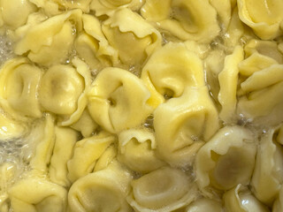 Fresh tortellini cooking in bubbling water, creating a delightful aroma and texture in a home...