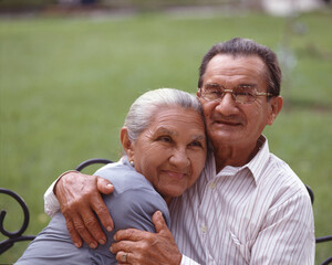 Grandparents couple hugging sitting on outdoors park.