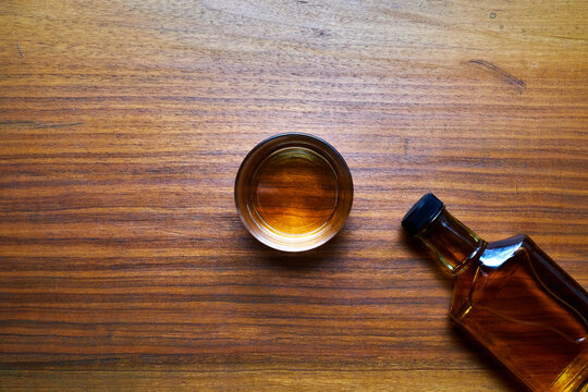 Whiskey bottle and glass on a wooden table.