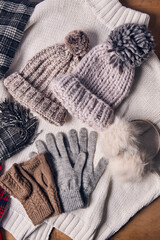 Cozy knit hats, gloves, scarves, and earmuffs displayed on knitted sweater, showcasing winter fashion essentials with soft textures and neutral colors. Concept of cozy winter, style, aesthetic, relax.