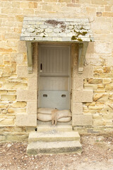 Door with sandbags and weathering on beach house wall made of granite and sandstone, Cornwall, England