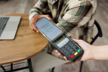 Cropped young man in casual clothes hold wireless bank payment terminal process acquire blank...