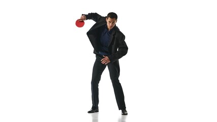 Man in black suit holding red ping-pong paddle in dynamic stance, representing agility and focus against white studio background. Concept of business, work-life balance, leadership, multitasking.