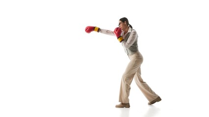 Focused woman in gray vest and beige trousers steps into precise boxing stance, symbolizing determination and adaptability. Concept of business agility, work-life balance, leadership, multitasking.