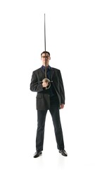 Businessman standing confidently with fencing sword, representing discipline, sharp intellect, and power in decision-making processes against white studio background. Concept of leadership.