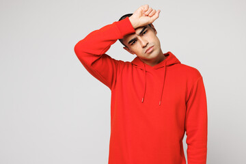 Young sad sick ill exhausted middle eastern man he wear red hoody casual clothes put hand on forehead suffer from headache isolated on plain solid white background studio portrait. Lifestyle concept.